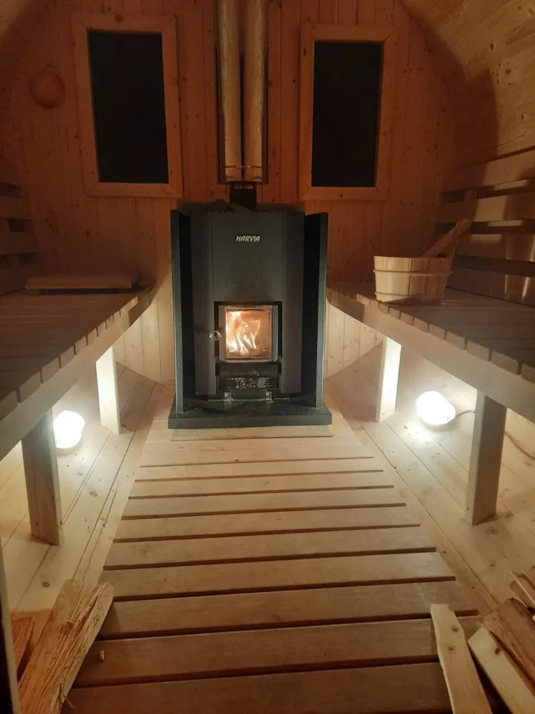 Blick in die Fasssauna auf den Harvia-Holzofen zwischen den Bänken