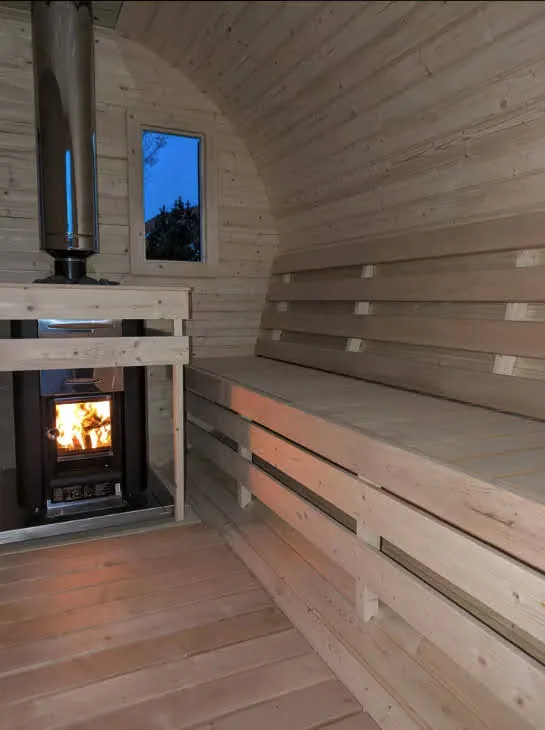 Innenraum der Fasssauna mit brennendem Holzofen und Holzbänken