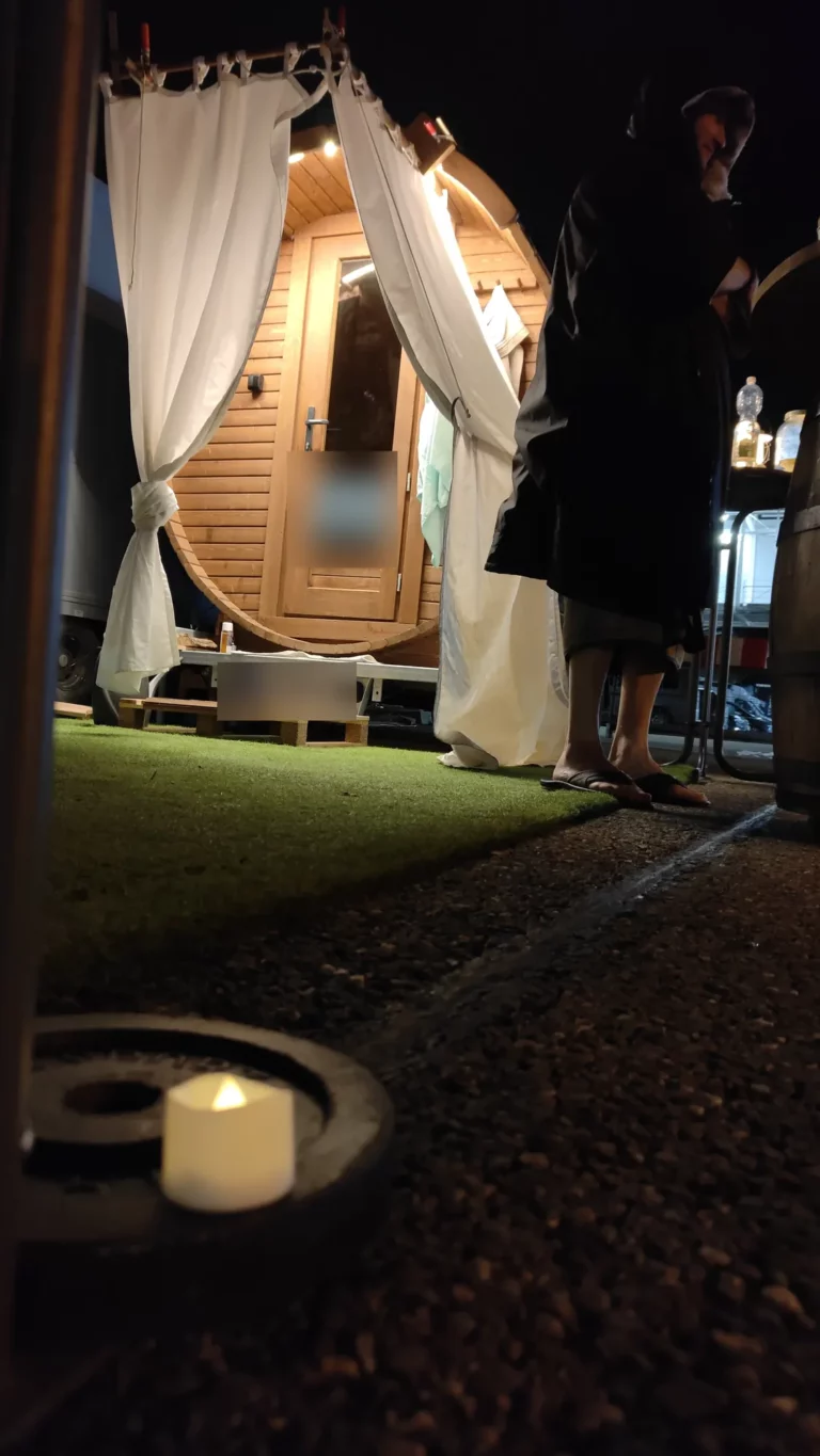 Fasssauna am Abend mit Vorhängen und Kerzenlicht