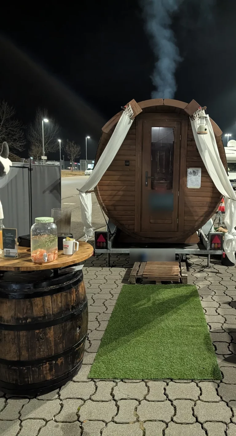 Mobile Sauna beim Event am Abend, Rauch steigt aus dem Ofenrohr