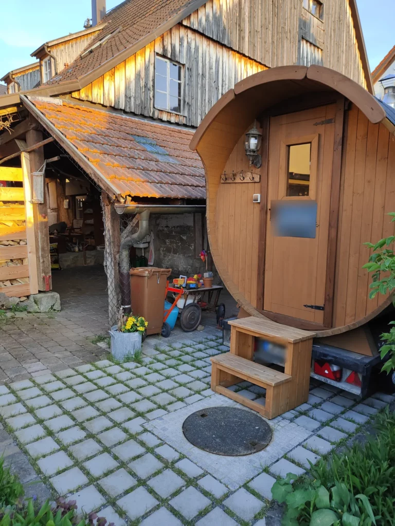 Eingang der Fasssauna mit Holztreppe im Innenhof