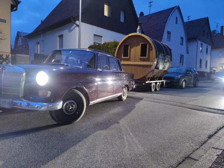 Oldtimer zieht die mobile Fasssauna auf dem Anhänger